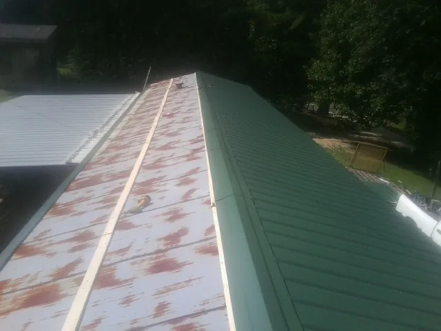 Old rusted panels beside newly installed green metal roofing — Wind Damage Roof Repair by Roofing Brothers in Fletcher