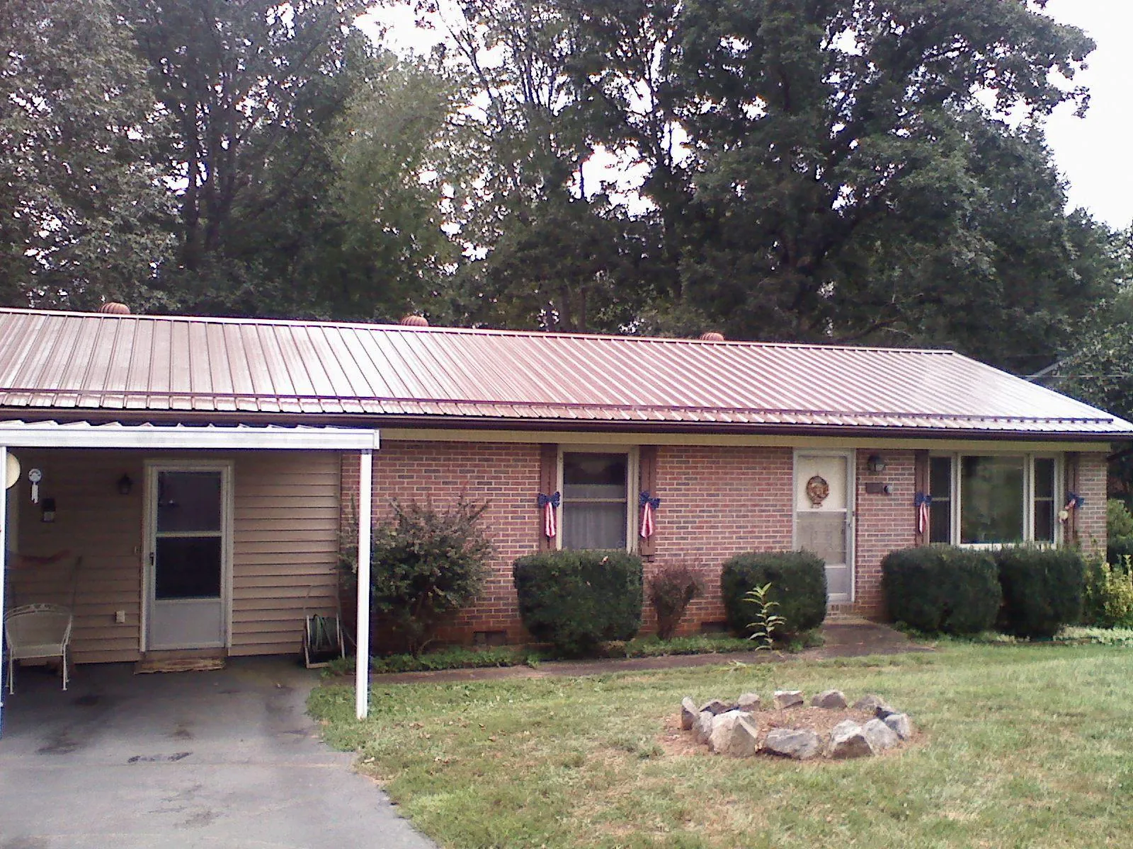Bronze metal roof and carport on a brick ranch home — Roof Repair work by our crew in Fletcher