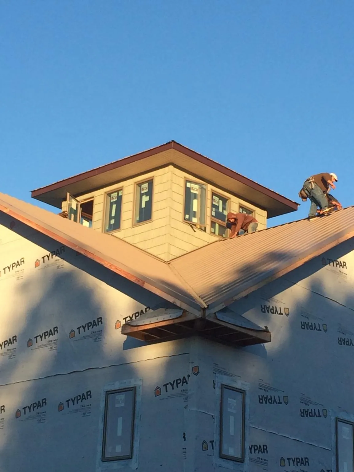 Roofers working around a rooftop cupola on a new metal roof at sunset — Roof Waterproofing in Fletcher by Roofing Brothers